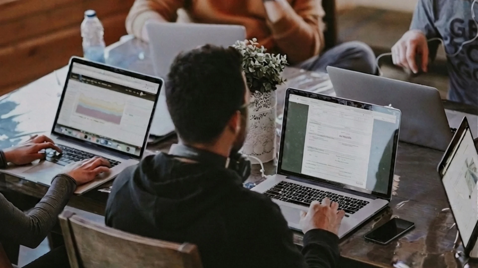 A team working on laptops around a table, one screen showing a chart