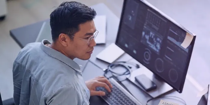 An engineer in glasses working at a monitor showing a dashboard